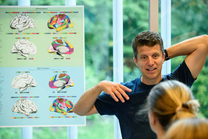 man infront of a poster with illustrations of the brain